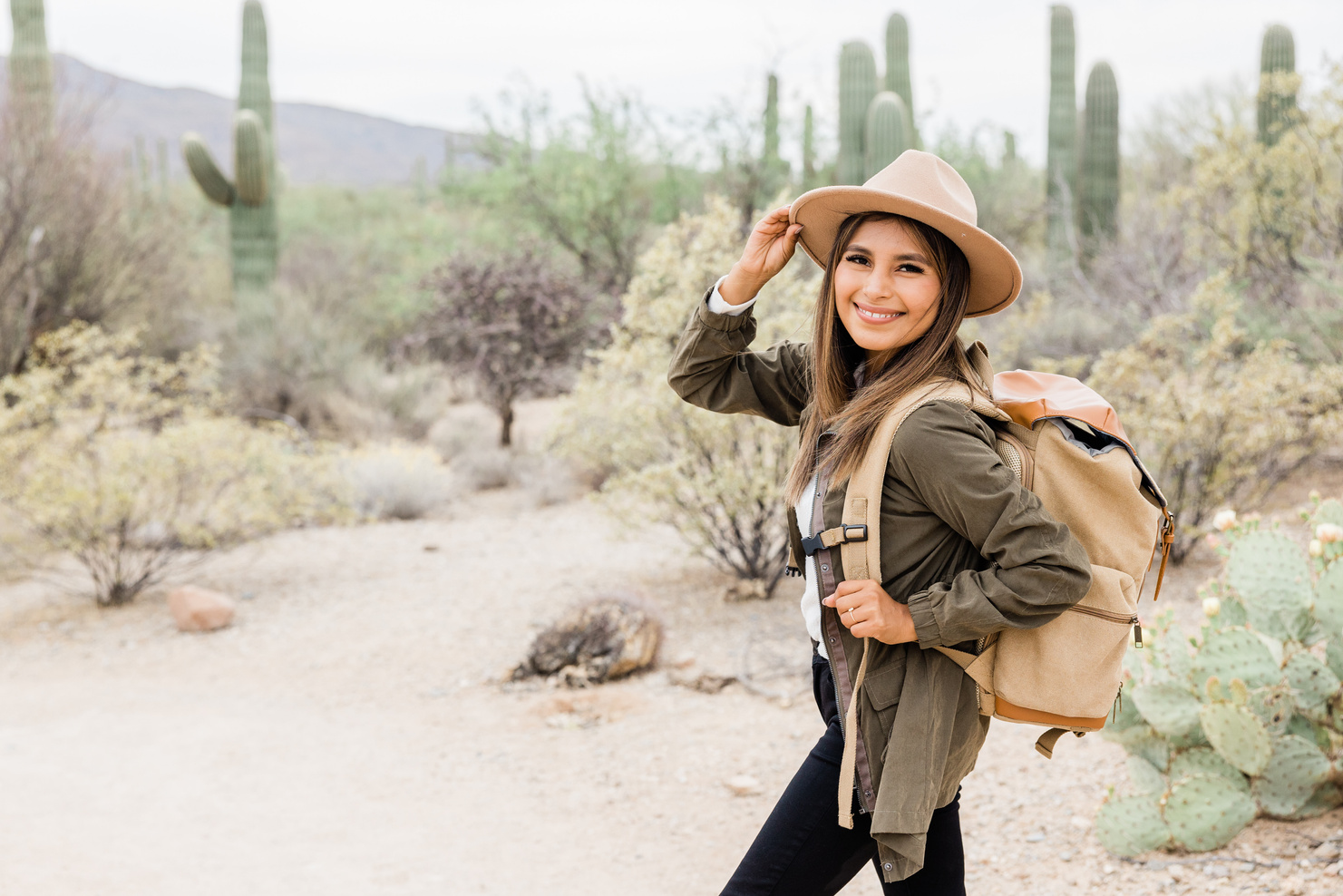 Smiling Woman in Hat and Backpack in a Desert